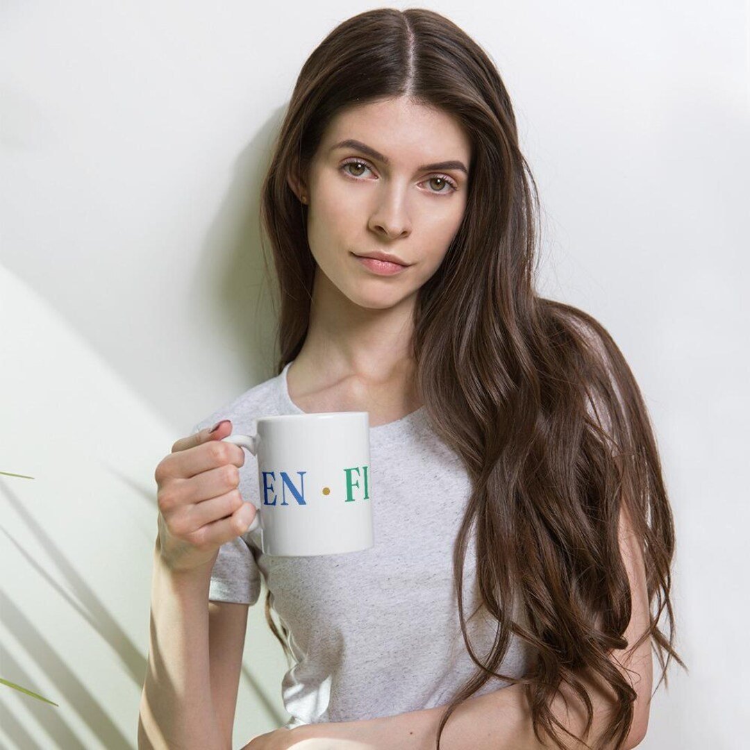 Glossy white ceramic coffee mug with the Enfiaré wordmark printed on the side.